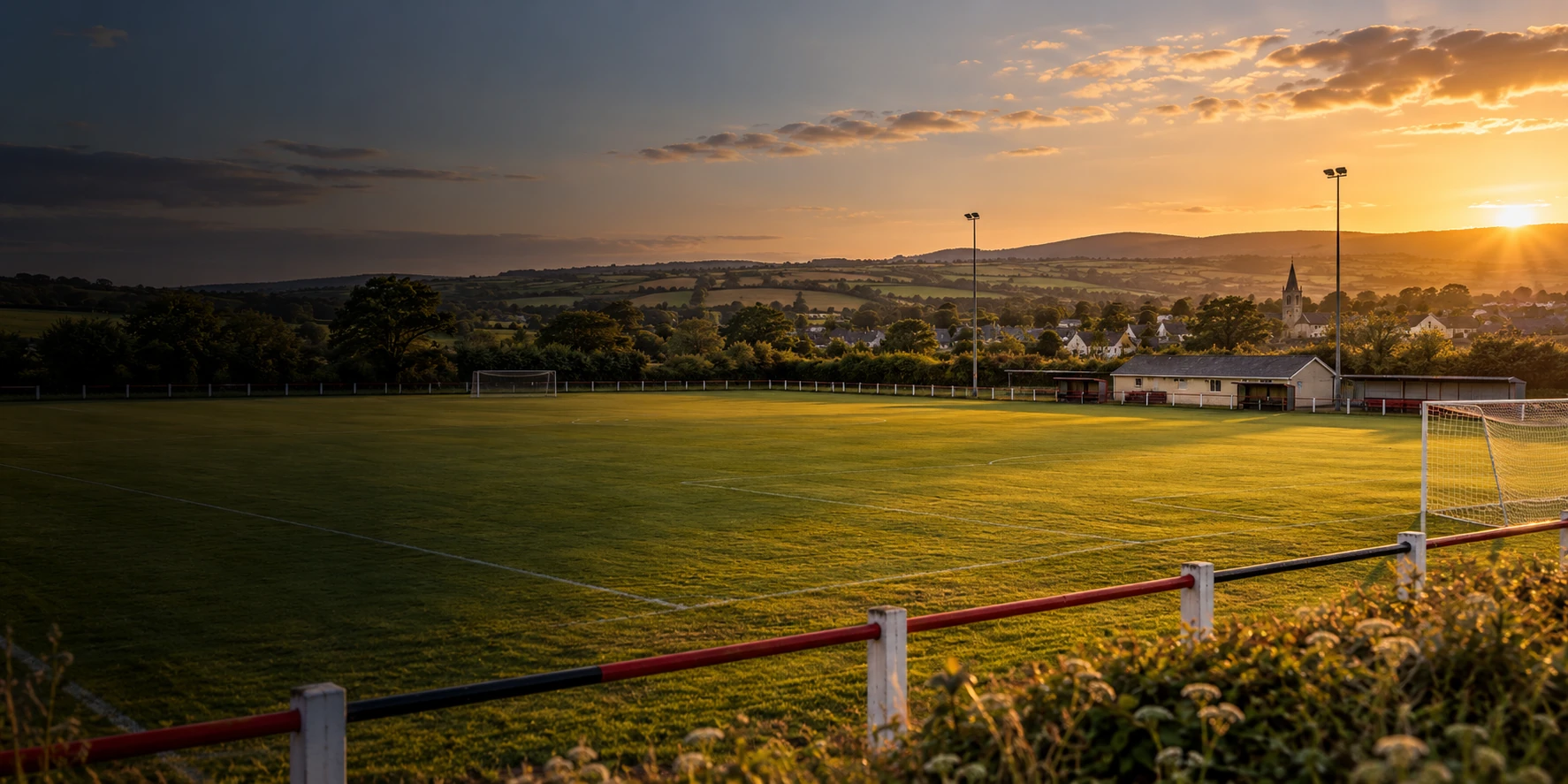 Dunlavin AFC crest over a Wicklow football pitch at sunset