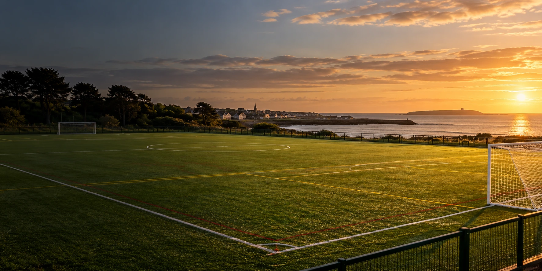 Rush Athletic FC crest over a football pitch beside the coast in Rush